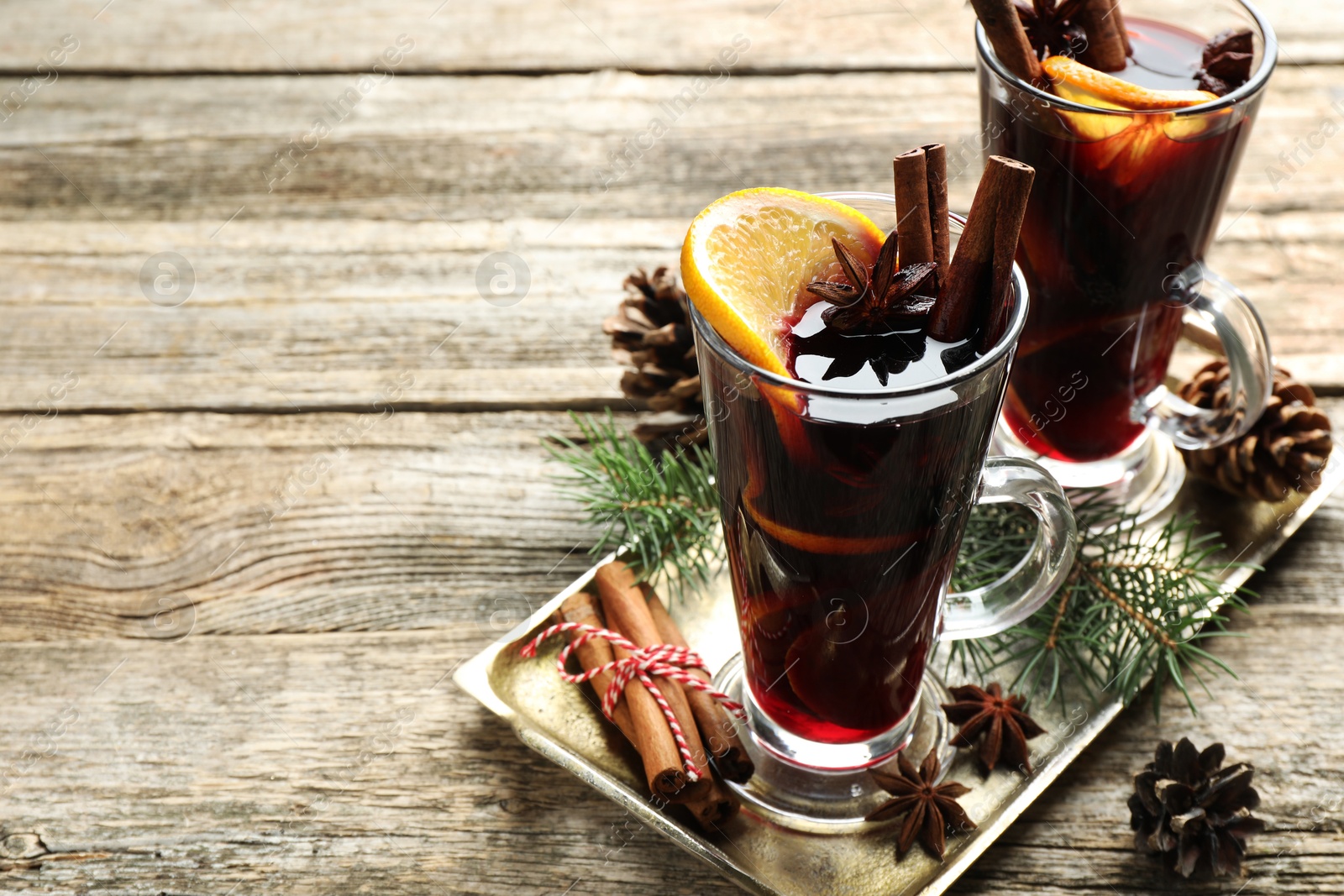 Photo of Tasty mulled wine with spices and Christmas decor on wooden table. Space for text