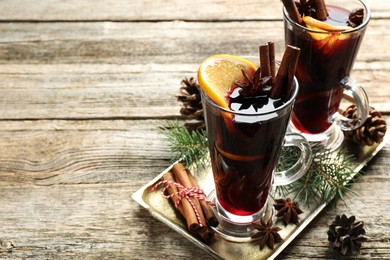 Photo of Tasty mulled wine with spices and Christmas decor on wooden table. Space for text