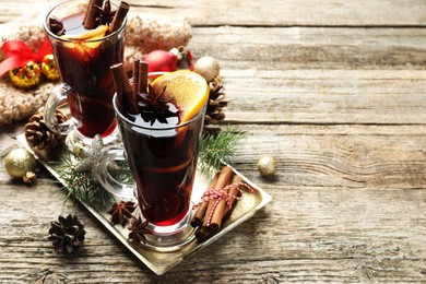 Photo of Tasty mulled wine with spices and Christmas decor on wooden table. Space for text