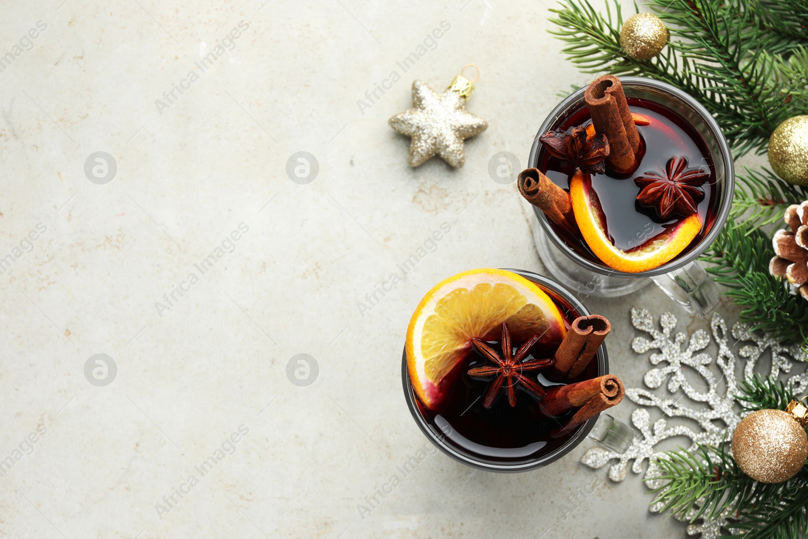 Photo of Tasty mulled wine with spices and Christmas decor on light grey table, flat lay. Space for text