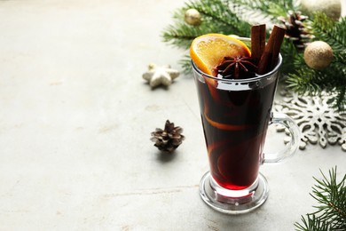 Photo of Tasty mulled wine with spices and Christmas decor on light grey table, closeup. Space for text