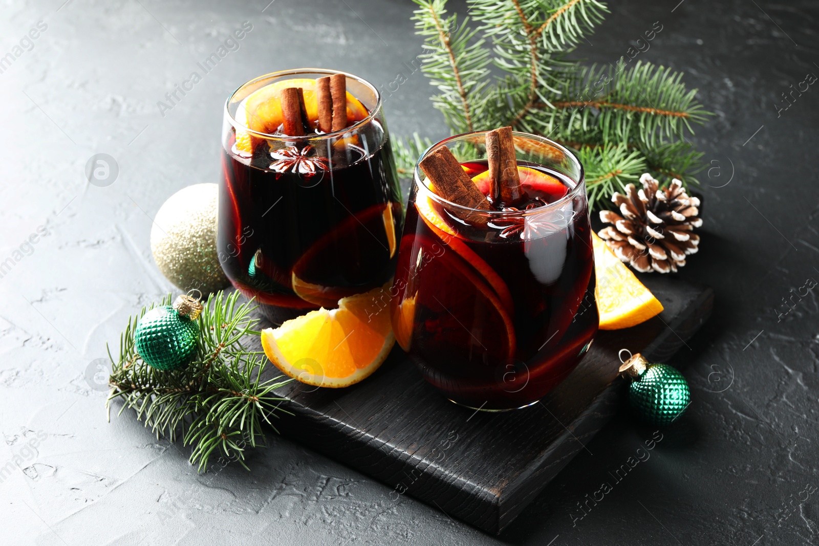 Photo of Tasty mulled wine with spices and Christmas decor on black table