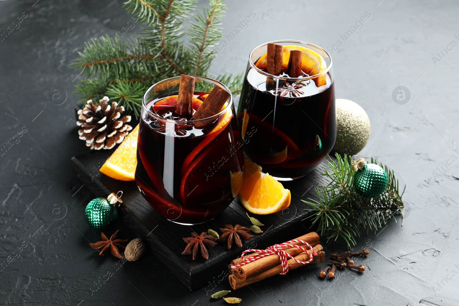 Photo of Tasty mulled wine with spices and Christmas decor on black table