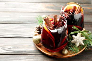 Photo of Tasty mulled wine with spices and Christmas decor on wooden table, closeup. Space for text