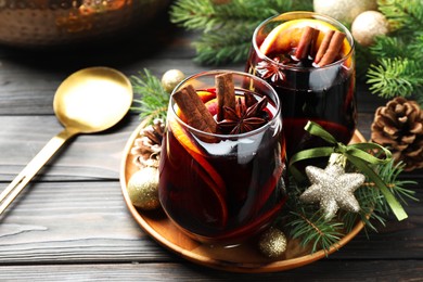 Photo of Tasty mulled wine with spices and Christmas decor on wooden table, closeup