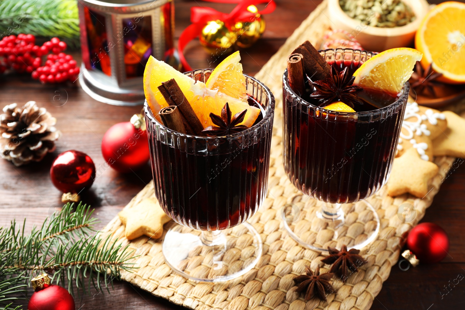 Photo of Tasty mulled wine with spices and Christmas decor on wooden table, closeup