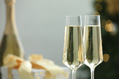 Photo of Champagne in glasses with decor against blurred Christmas lights, closeup and space for text. Bokeh effect