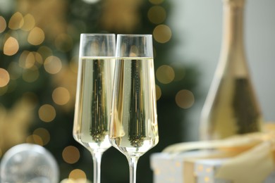 Photo of Champagne in glasses and decor against blurred Christmas lights, closeup. Bokeh effect