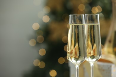 Photo of Champagne in glasses with decor against blurred Christmas lights, closeup and space for text. Bokeh effect