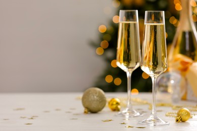 Photo of Champagne in glasses and Christmas decor on white wooden table against blurred lights, space for text. Bokeh effect