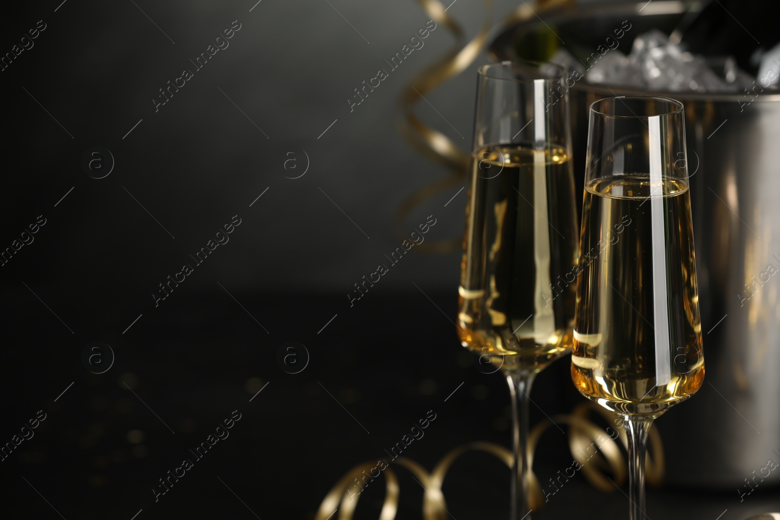 Photo of Champagne in glasses with decor on black table, closeup and space or text. Christmas celebration