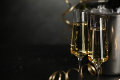 Photo of Champagne in glasses with decor on black table, closeup and space or text. Christmas celebration