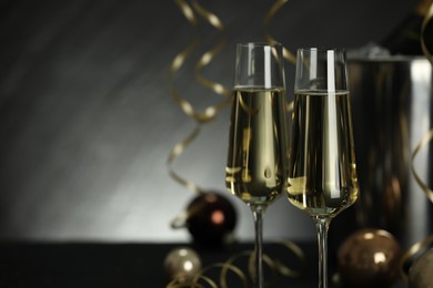 Photo of Champagne in glasses with decor on black table, closeup and space or text. Christmas celebration