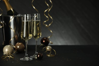 Photo of Champagne in glasses and decor on black table, space or text. Christmas celebration