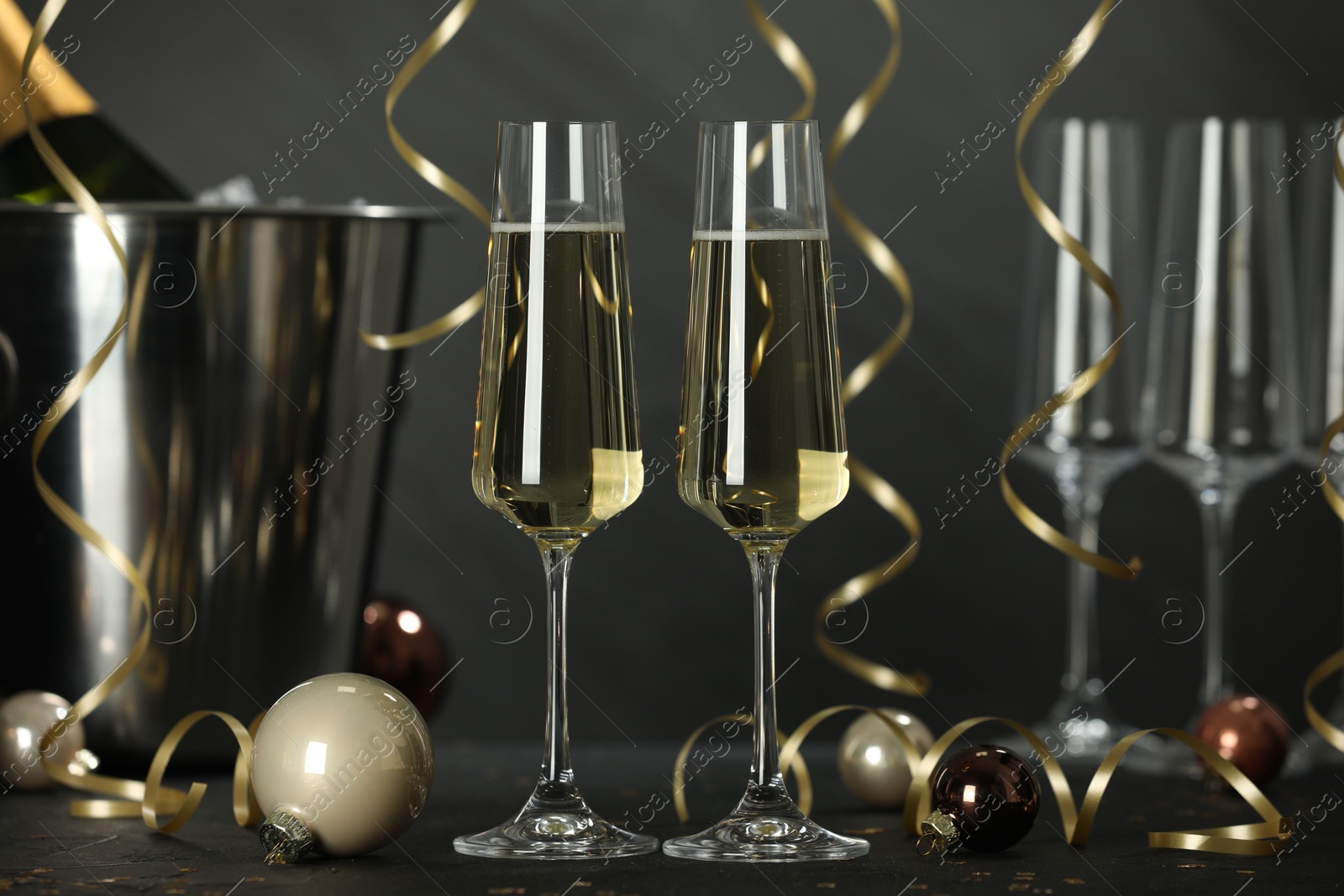 Photo of Champagne in glasses and Christmas decor on black table