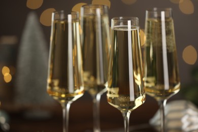 Photo of Champagne in glasses and decor on dark background blurred Christmas lights, closeup. Bokeh effect