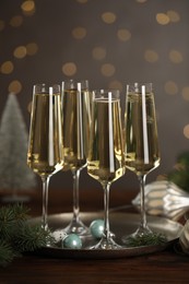 Photo of Champagne in glasses and Christmas decor on wooden table against blurred lights. Bokeh effect