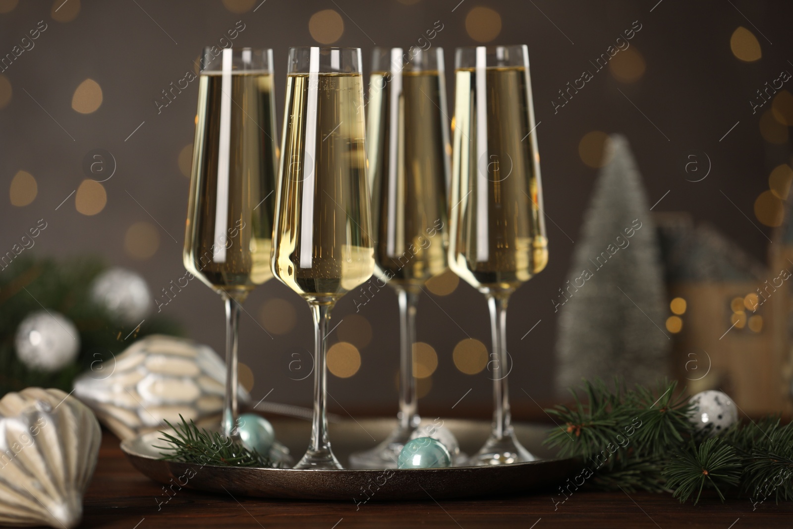 Photo of Champagne in glasses and Christmas decor on wooden table against blurred lights. Bokeh effect