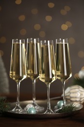 Photo of Champagne in glasses and Christmas decor on wooden table against blurred lights. Bokeh effect