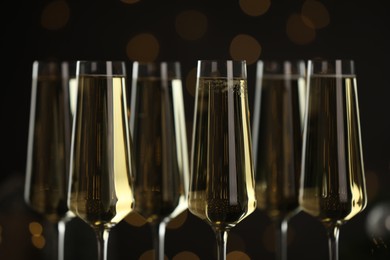 Photo of Champagne in glasses on dark background with blurred Christmas lights, closeup. Bokeh effect