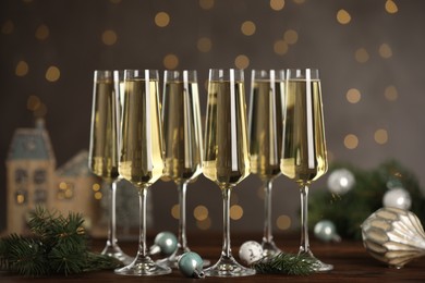 Photo of Champagne in glasses and Christmas decor on wooden table against blurred lights. Bokeh effect