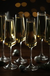 Photo of Champagne in glasses and decor on wooden table against blurred Christmas lights. Bokeh effect