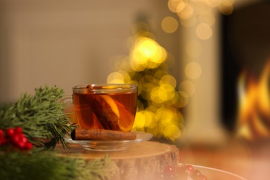 Photo of Cup of tea with lemon and cinnamon on table against blurred Christmas lights, bokeh effect. Space for text