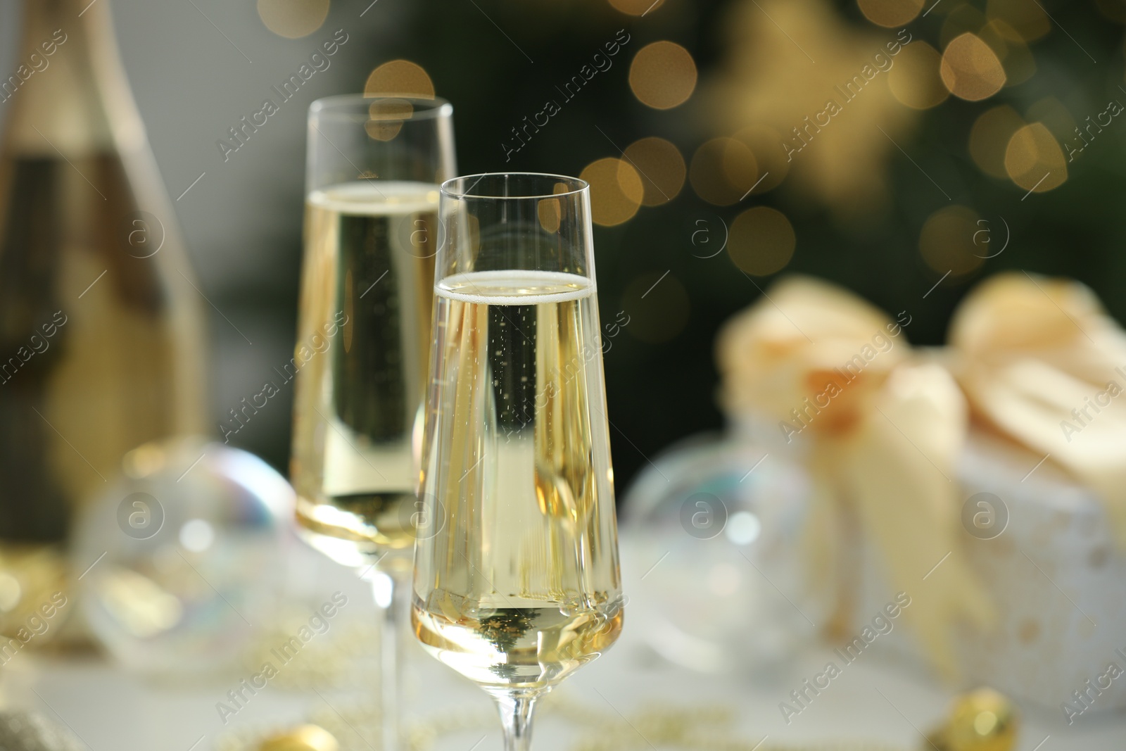 Photo of Champagne in glasses and decor against blurred Christmas lights, closeup. Bokeh effect