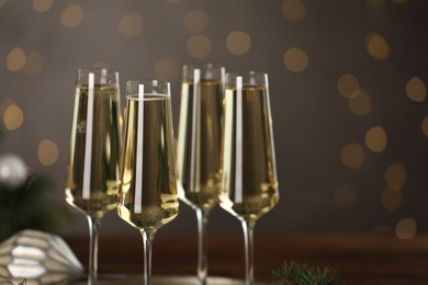 Photo of Champagne in glasses on dark background blurred Christmas lights, closeup. Bokeh effect