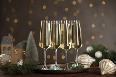 Photo of Champagne in glasses and Christmas decor on wooden table against blurred lights. Bokeh effect