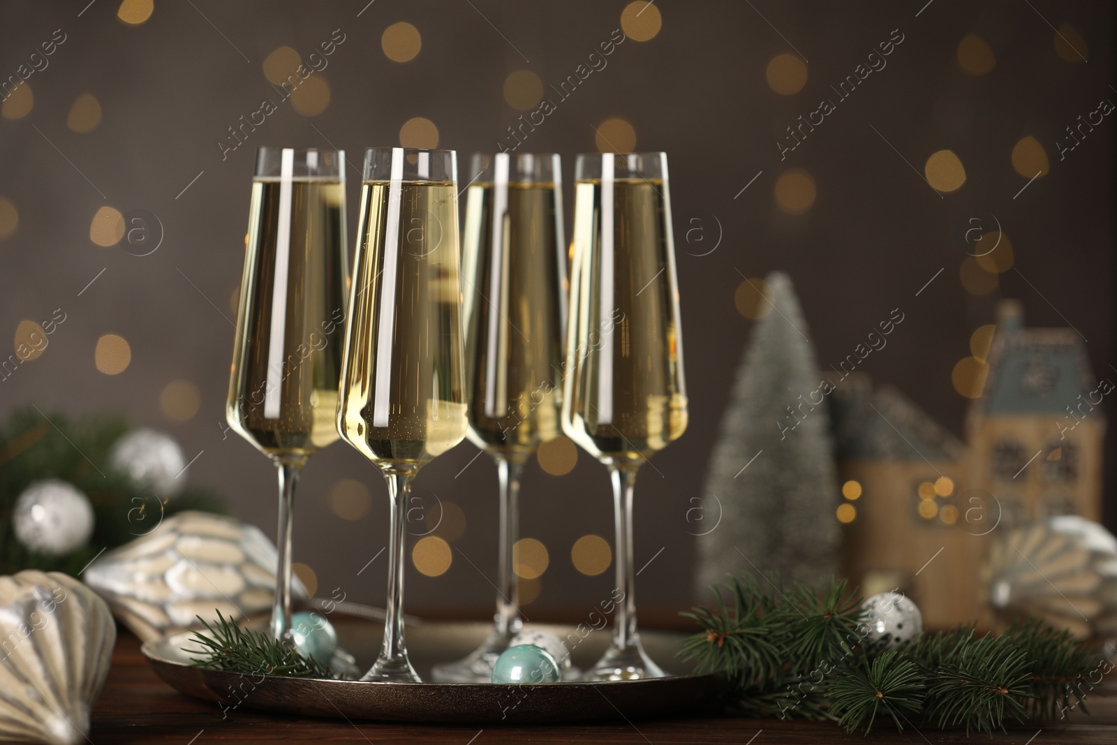 Photo of Champagne in glasses and Christmas decor on wooden table against blurred lights. Bokeh effect