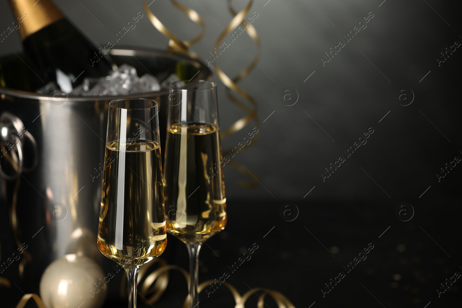 Photo of Champagne in glasses with decor on black table, closeup and space or text. Christmas celebration