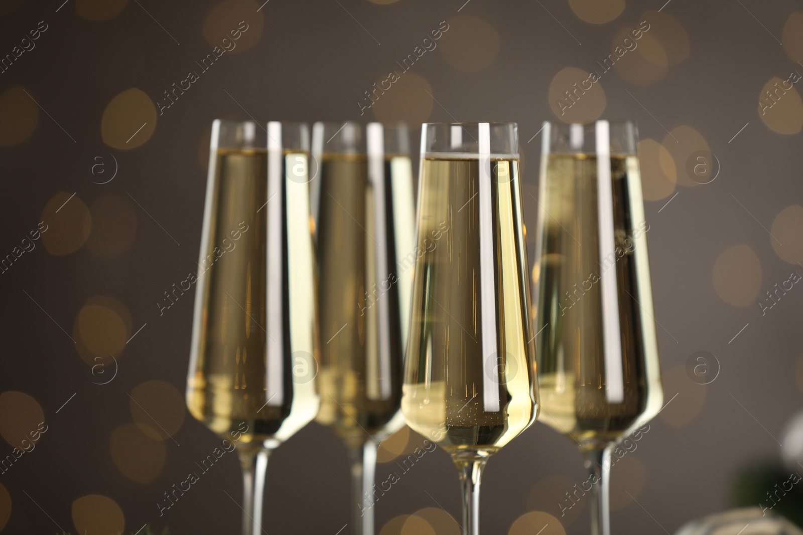 Photo of Champagne in glasses on dark background blurred Christmas lights, closeup. Bokeh effect