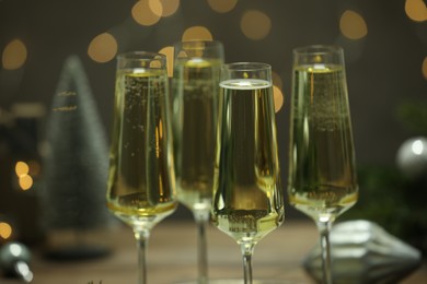 Photo of Champagne in glasses and decor on dark background blurred Christmas lights, closeup. Bokeh effect