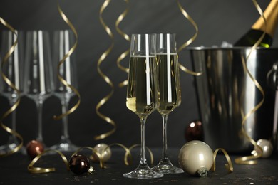 Photo of Champagne in glasses and Christmas decor on black table