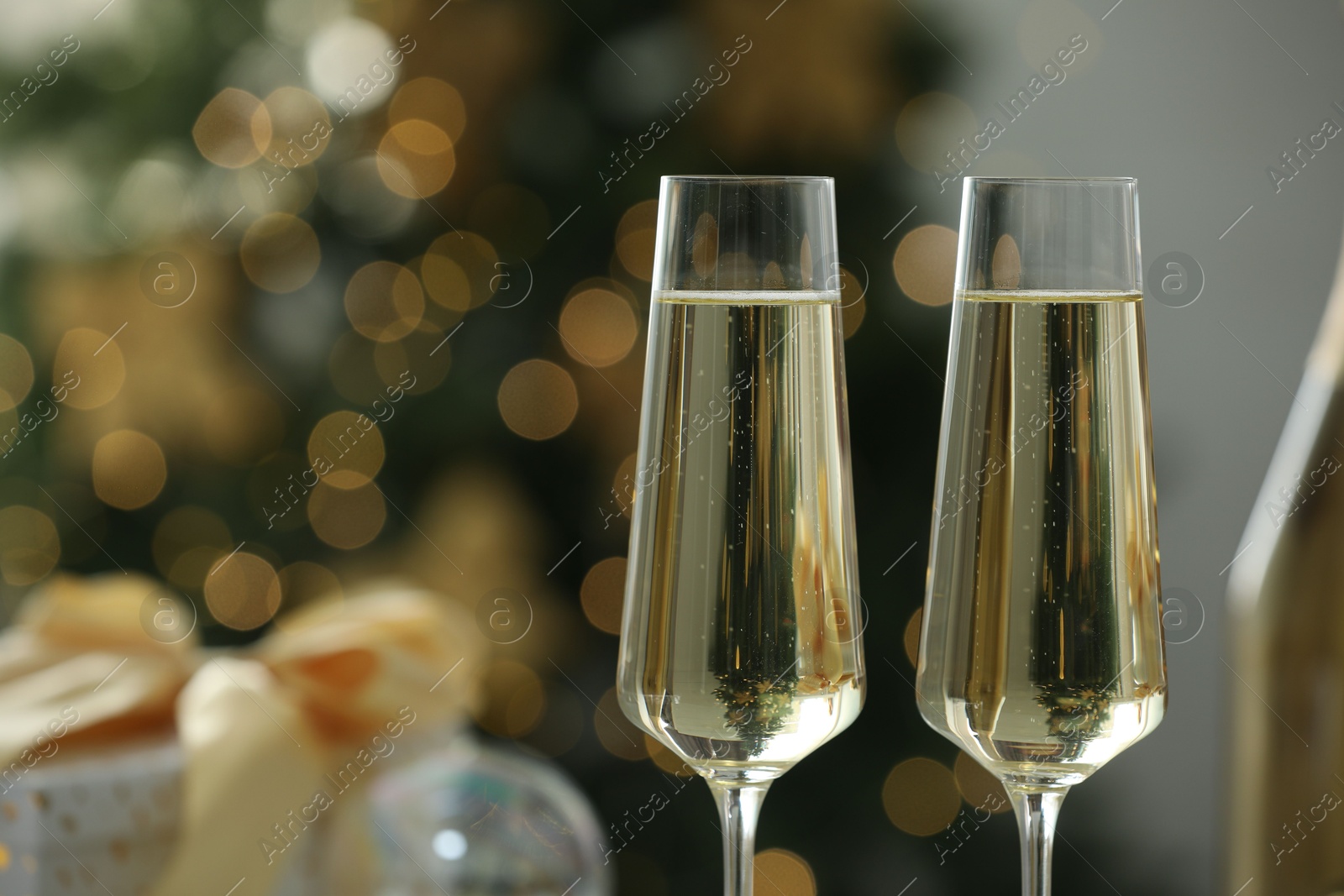 Photo of Champagne in glasses with decor against blurred Christmas lights, closeup and space for text. Bokeh effect