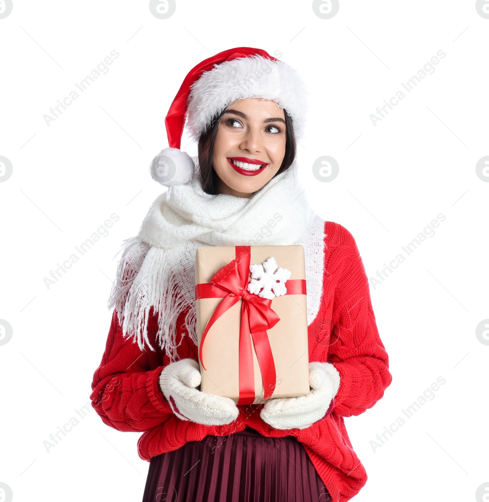 Photo of Woman in Santa hat, knitted mittens, scarf and red sweater holding Christmas gift on white background