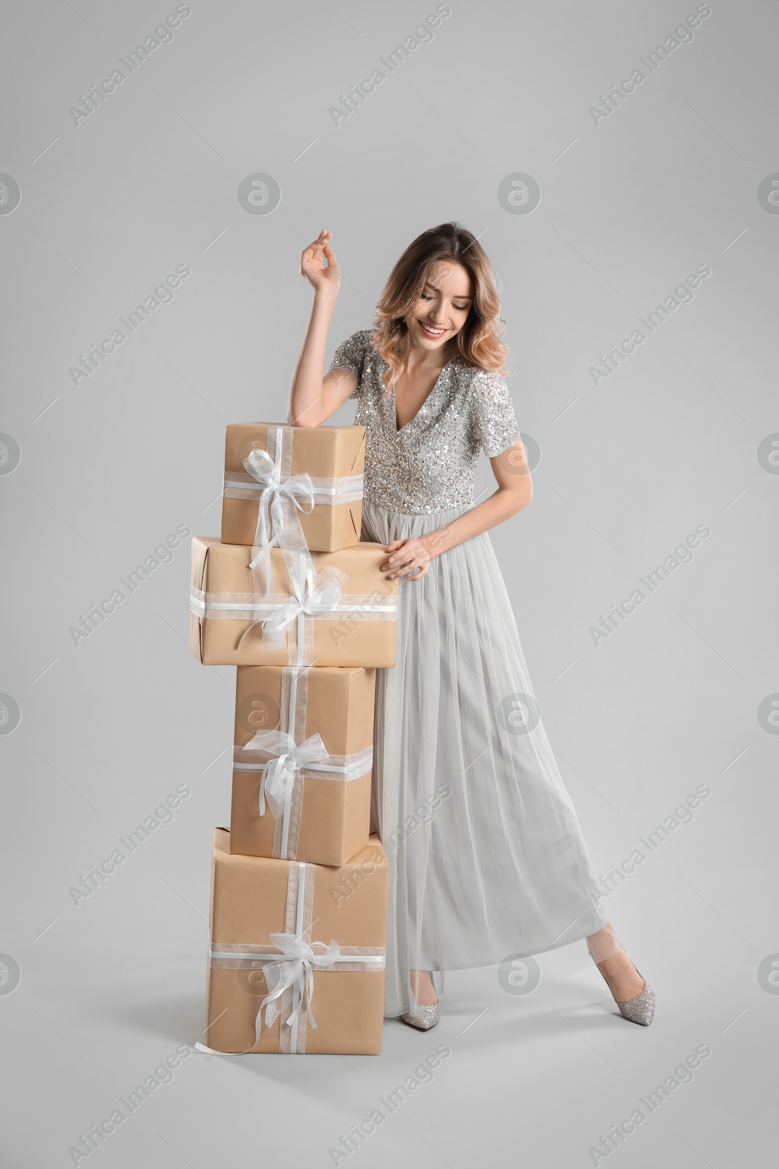 Photo of Beautiful young woman with Christmas presents on light grey background