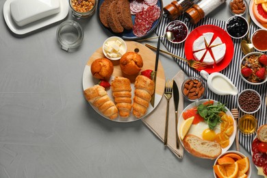 Photo of Different tasty food served for brunch on grey table, flat lay. Space for text