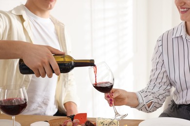 People with red wine and snacks indoors, closeup