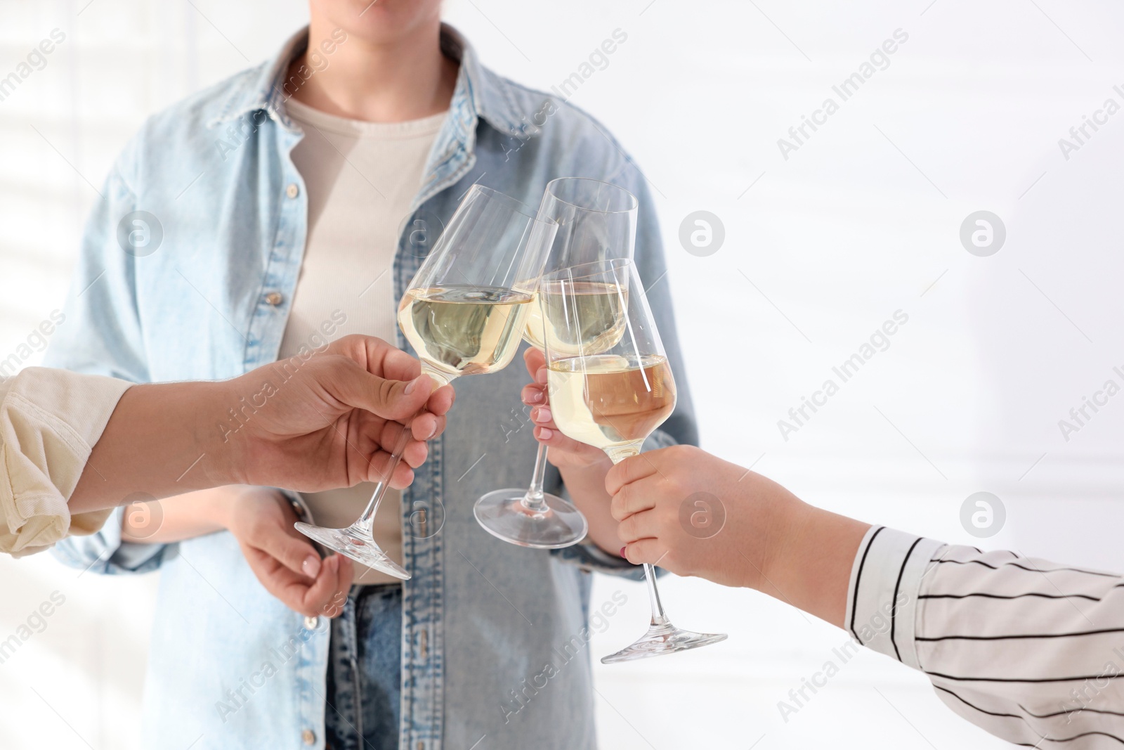 Photo of People clinking glasses of wine indoors, closeup