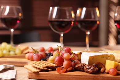 Photo of Glasses of red wine and different snacks on wooden table, selective focus