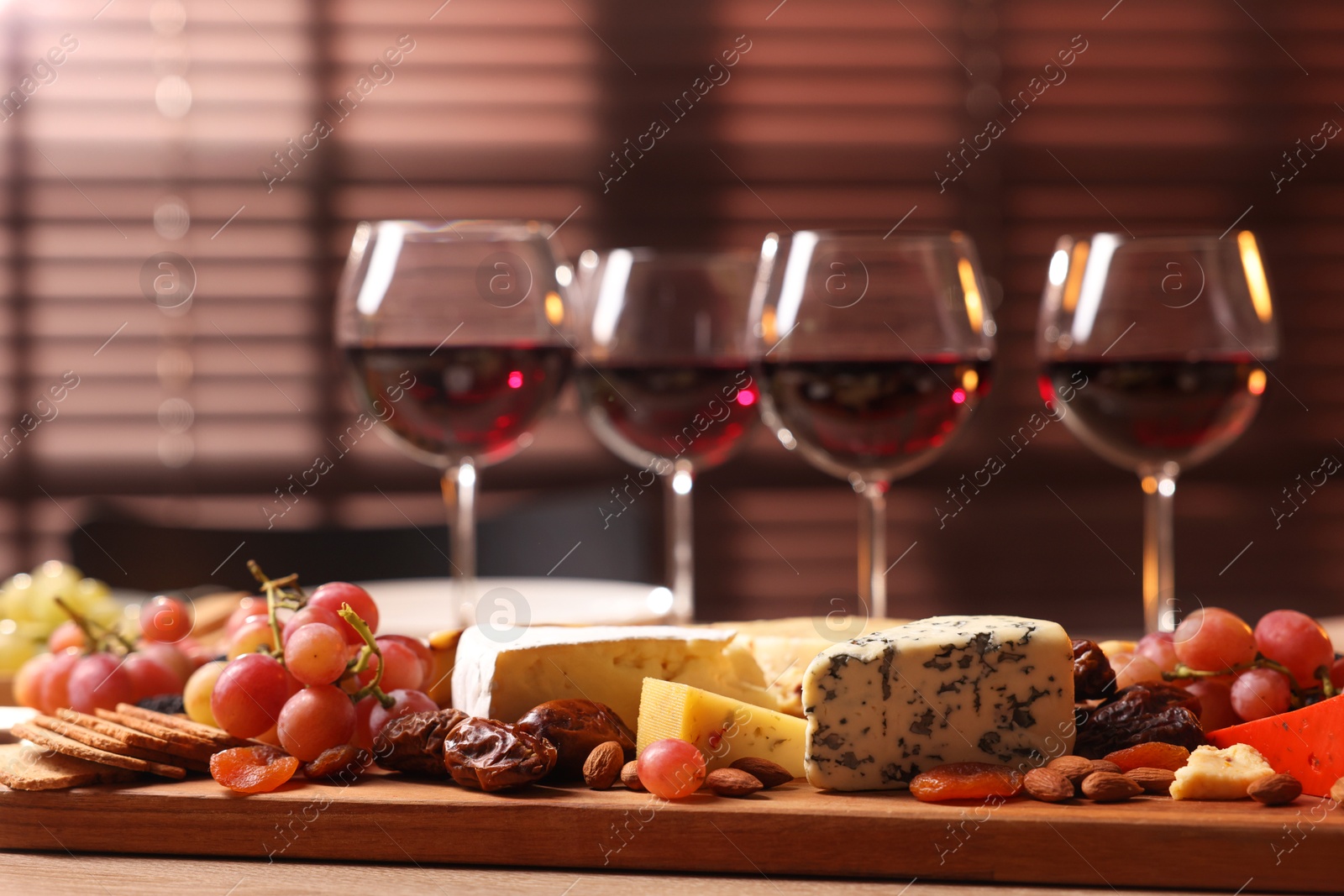 Photo of Glasses of red wine and different snacks on wooden table, selective focus