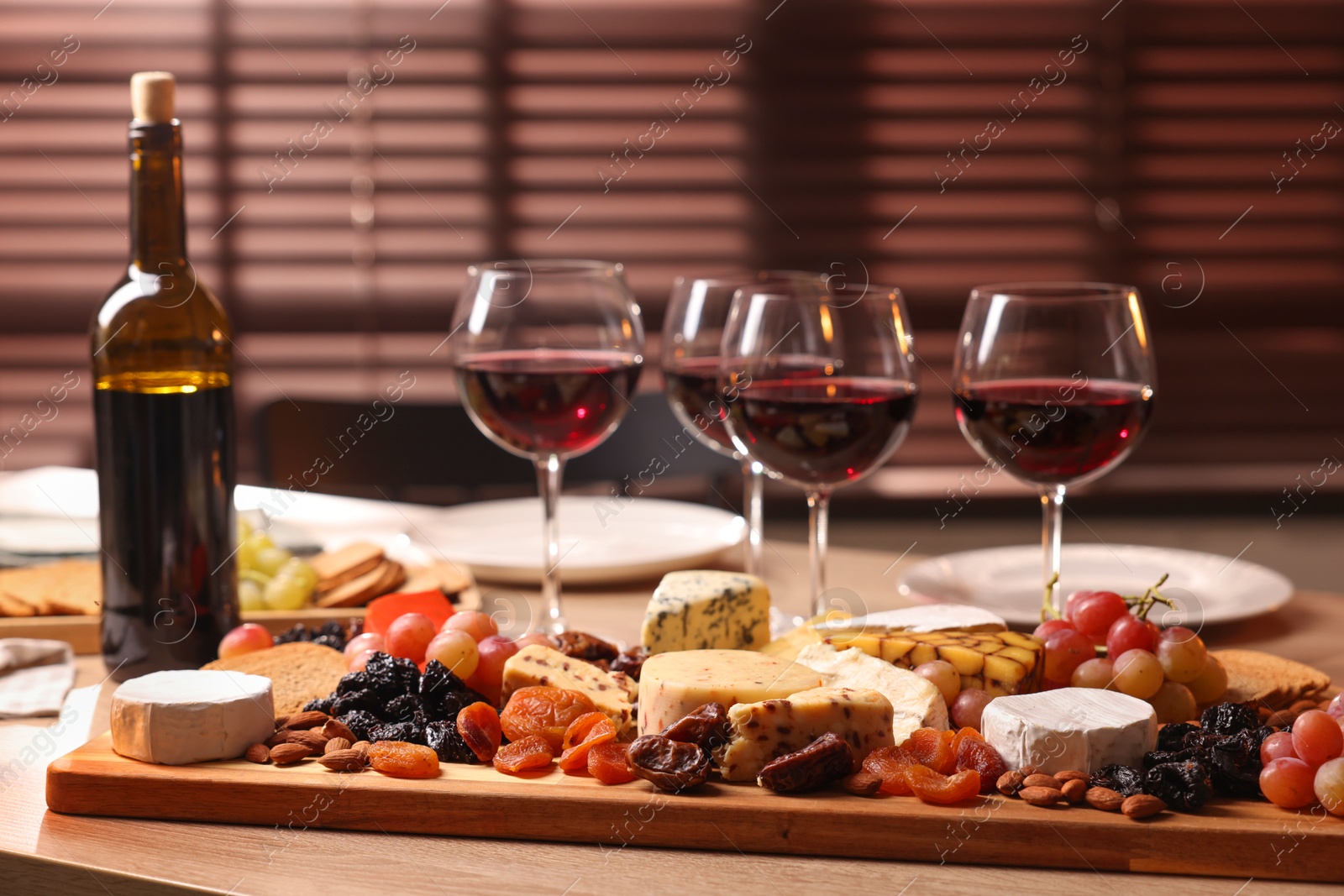 Photo of Glasses of red wine and different snacks on wooden table, selective focus