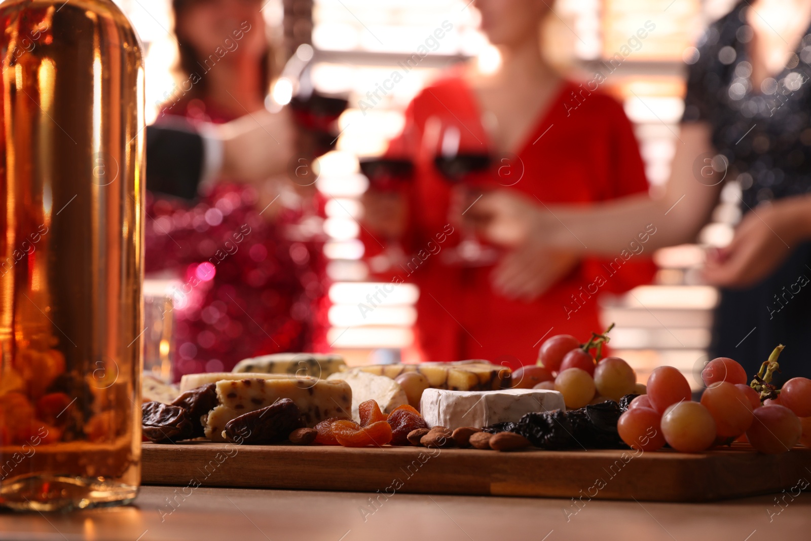 Photo of People clinking glasses of wine at party, focus on table with snacks