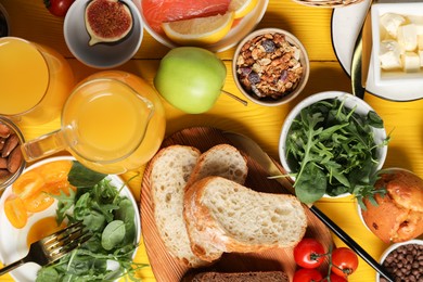 Photo of Different tasty food served for brunch on yellow wooden table, flat lay