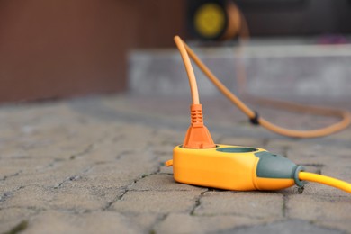 Photo of Extension cord on paved pathway outdoors, closeup. Space for text