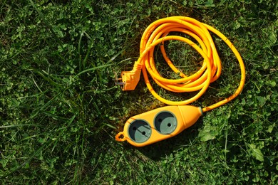 Photo of Orange extension cord on green grass outdoors, top view