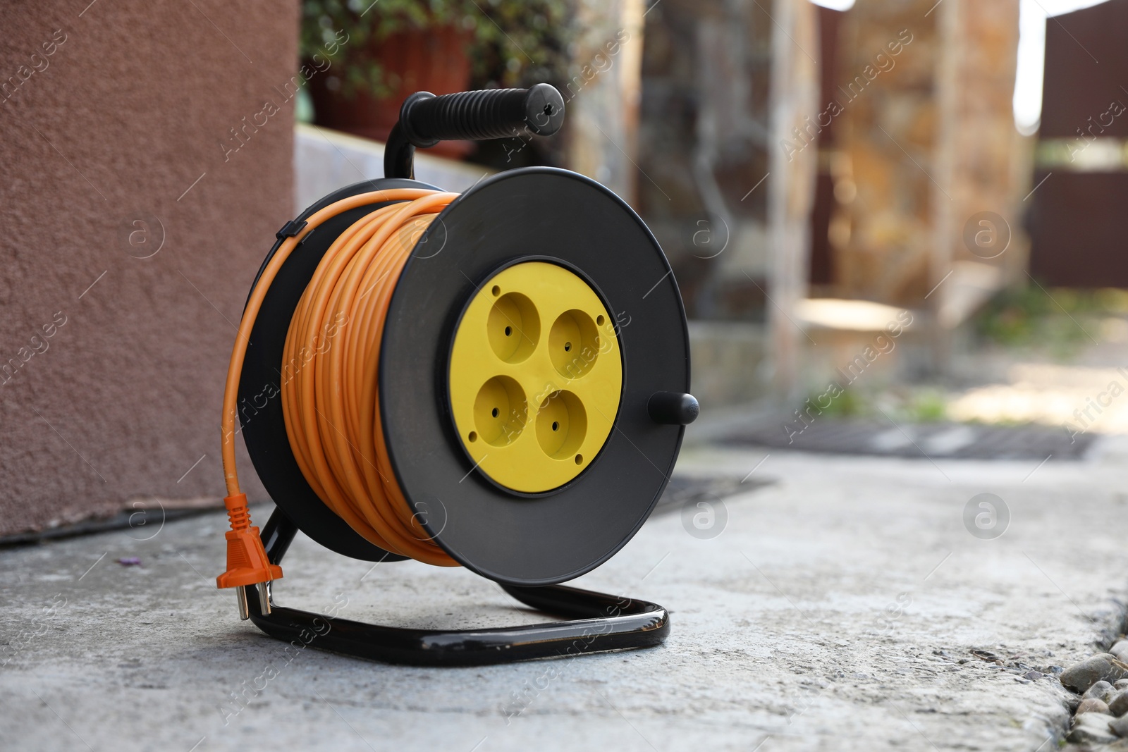 Photo of Extension cord reel on asphalt outdoors, space for text