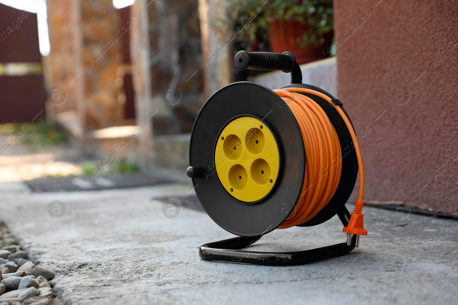 Photo of Extension cord reel on asphalt outdoors, space for text